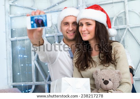 Christmas selfie.Young beautiful couple in love is making selfie in New Year decorated living room. Winter window is on the background