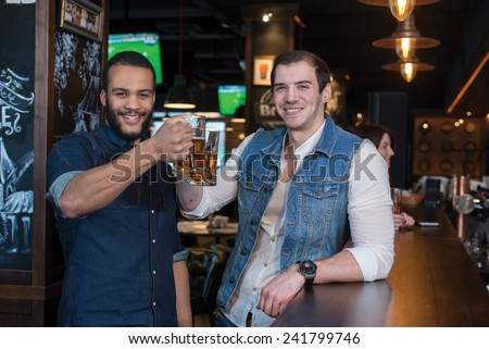 Friends are having fun with beer. Portrait of two handsome friends in a pub with glasses of beer