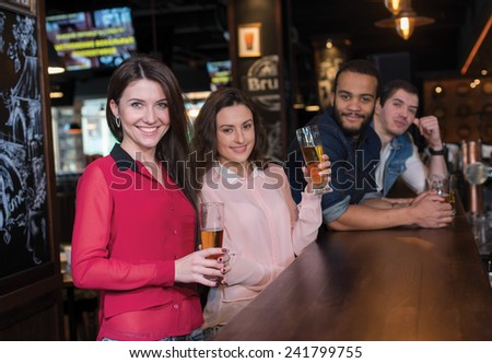 Friends and beer. Four friends are drinking beer in a pub. Girls and guys are smiling