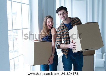 Entering new house. Young and beautiful couple is moving to new apartment surrounded with plenty of cardboard boxes.
