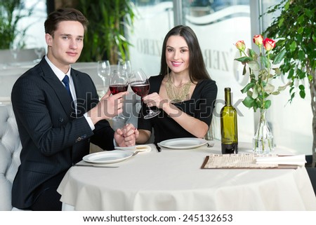 Smiling romantic couple in love is sitting in restaurant together and drinking wine
