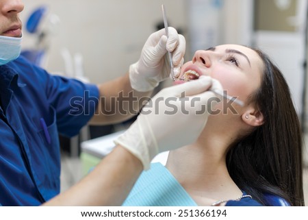 The perfect smile and perfect teeth. Confident professional doctor dentist is working with patient in dental chair in his medical dental office.