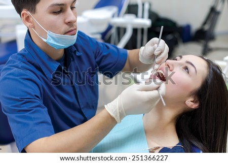 The perfect smile and perfect teeth. Confident professional doctor dentist is working with patient in dental chair in his medical dental office.