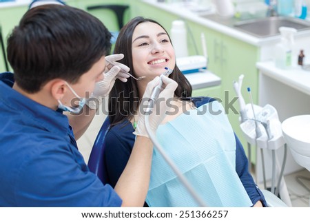 Dentist at work with his patient. Confident professional doctor dentist is working in his medical dental office. His female patient is smiling