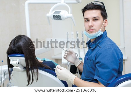 The perfect smile and perfect teeth. Confident professional doctor dentist is sitting and working with his female patient. Doctor wearing medical clothing.