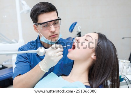 Healthy teeth and smiles. Confident professional doctor dentist is sitting and working with his female patient. Doctor wearing medical clothing.