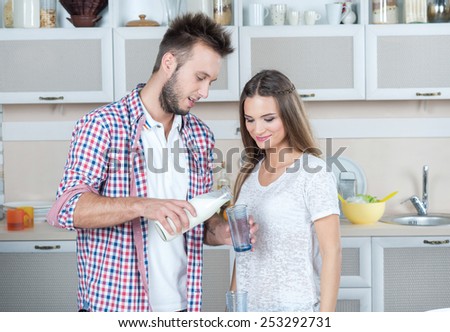 Love and milk on the kitchen. Young and beautiful couple in love is drinking milk on the kitchen, while preparing food. Dairy. Milk. Fun.
