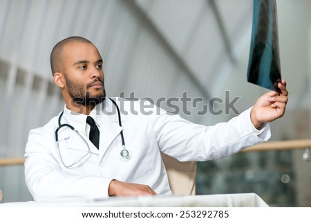 Doctor examining an x-ray of the patient. Portrait of a doctor of the therapist. Confident doctor holding x-ray shot. Doctor at work in a hospital
