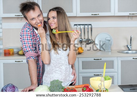 Best cooking food for lovers on the kitchen. Young and beautiful couple in love is preparing food in the kitchen while tasting some food