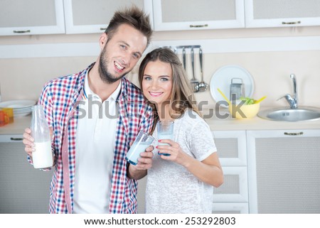 Love and milk on the kitchen. Young and beautiful couple in love is drinking milk on the kitchen, while preparing food. Dairy. Milk. Fun.