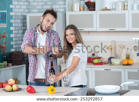 Some wine on the kitchen. Young and beautiful couple in love is preparing food on the kitchen, while opening bottle of wine. Diet. Dieting. Healthy vegetarian food