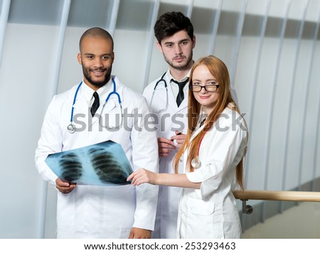 Healthy lungs and the danger of smoking. Three confident doctors examining x-ray snapshot of lungs in hospital. Team of doctors in hospital