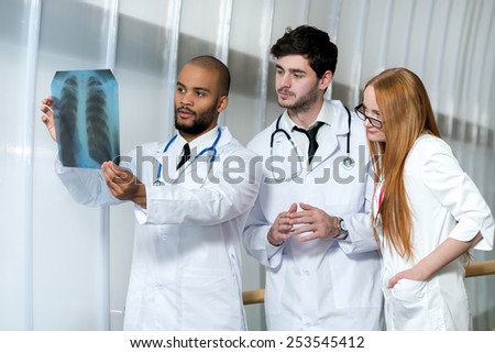 Working on x-ray of lungs of smoker. Three confident doctors examining x-ray snapshot of lungs in hospital. Team of doctors in hospital