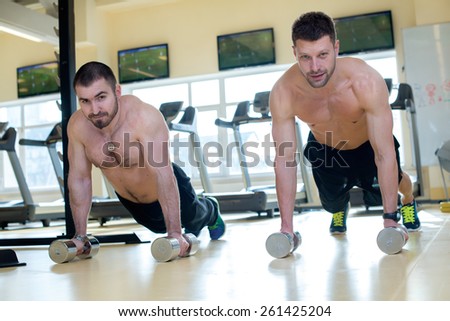 Good workout. Professional trainer and client in a fitness gym are having training. Both are doing pushups