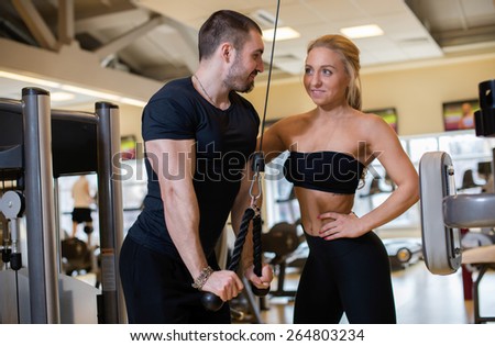 Great sport shape. Portrait of young and handsome athlete muscular guy in a gym. He is having an intensive workout and communicating with his female athlete female friend