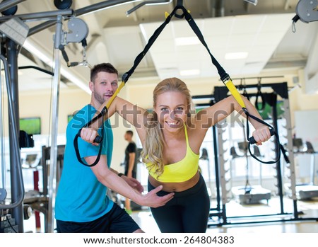 Perfect shape. Young and pretty girl is having training with her handsome athlete trainer. Active workout. Suspension training