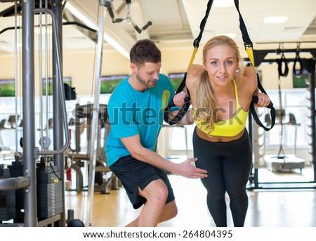 Perfect shape. Young and pretty girl is having training with her handsome athlete trainer. Active workout. Suspension training