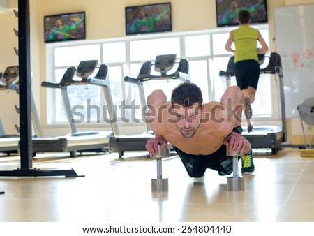 Perfect shape and ideal workout. Young and handsome athlete man is having a workout in a gym. Press ups.