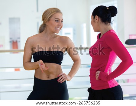 Intensive female training together. Couple of young and beautiful women are having workout in a gym. Perfect shape. Sportsmen. Good workout in a gym. Communication and sport