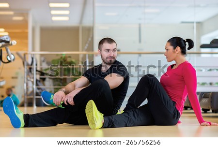 Intensive training together. Couple of young and beautiful people is having workout in a gym. Both are stretching together. Perfect shape. Sportsmen. Good workout in a gym