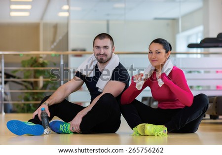 Intensive training together. Couple of young and beautiful people is having workout in a gym. Both are having rest after good workout. Perfect shape. Sportsmen. Hard workout in a gym
