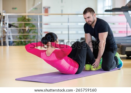 Intensive training together. Couple of young and beautiful people is having workout in a gym. Both are having abdominals training. Perfect shape. Sportsmen. Good workout in a gym