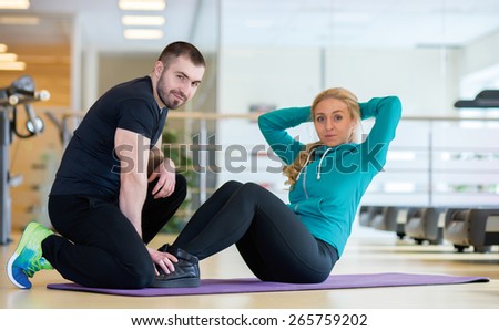 Intensive training together. Couple of young and beautiful people is having workout in a gym. Both are having abdominals training. Perfect shape. Sportsmen.