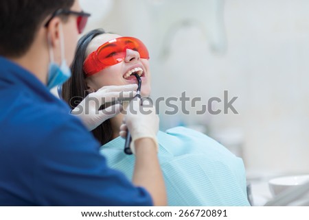 Healthy teeth and dental healthcare. Confident professional doctor dentist is working with pretty female patient. Doctor stomatologist is wearing medical clothing and glassess. Stomatology