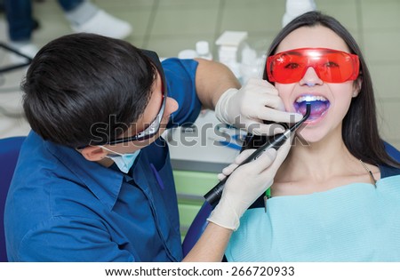 Healthy teeth and dental healthcare. Confident professional doctor dentist is working with pretty female patient. Doctor stomatologist is wearing medical clothing. Stomatology hygienist.