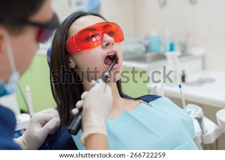 Healthy teeth and dental healthcare. Confident professional doctor dentist is working with pretty female patient. Doctor stomatologist is wearing medical clothing and glassess. Stomatology