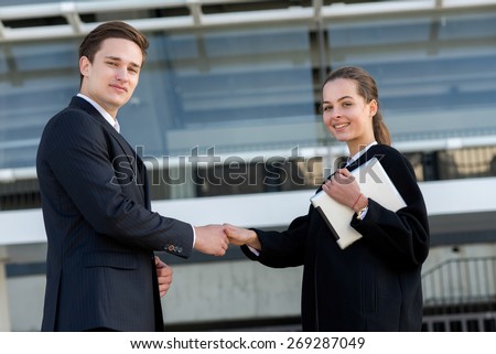 Well done business deal. Portrait of two confident and motivated partners. Man and woman are shaking hands, both have agreement on essential business project. Outdoor business concept