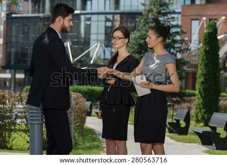 Discussion of project details. Three confident and motivated business partners are discussing future business forum. Both are wearing formal suits. Outdoor business concept