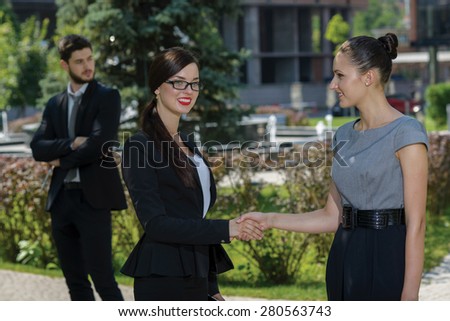 Excellent business agreement. Three confident and motivated business woman are shaking hands. Both are wearing formal suits. Outdoor business concept