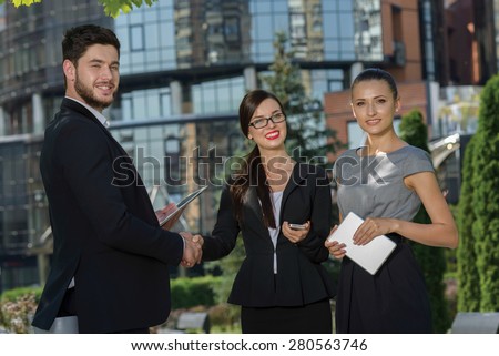 Perfect business relationship. Three confident and motivated business partners are discussing future business details and shaking hands. All are wearing formal suits. Outdoor business concept