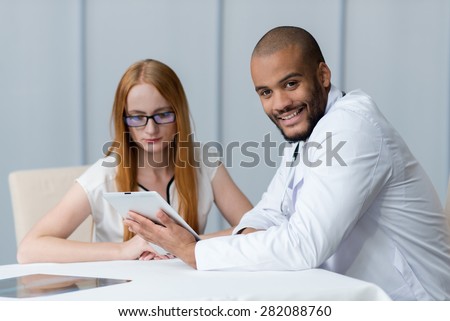 Portrait of a doctor of the therapist. Confident doctor is at work with his ill patient wearing white doctor clothes. Man is holding tablet. Medical concept