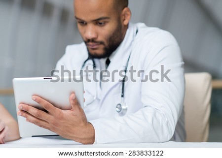 Close up of tablet. Doctor in white medical clothes is holding tablet in hospital. Medical concept.