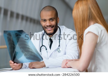 Doctor is examining x-ray in a hospital. Portrait of confident and professional doctor therapist wearing white medical clothes with his patient. Medical hospital concept.