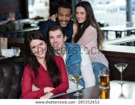 Perfect beer party in a pub. Portrait of beautiful couple drinking in a bub alcohol cocktails and beer. Both are smiling and have a fun. Beer pub concept