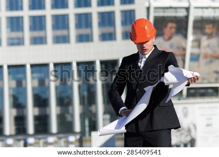 New building project fail. Young professional architect in protective helmet is furious because of mistake in blueprints. Business architects concept