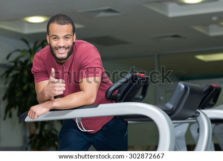 Perfect shape in a gym. Young and handsome African man is having training on a treadmill. Active workout. Healthy sportsmen concept