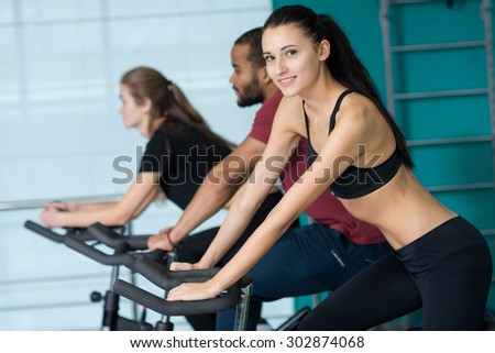 Perfect shape in a gym. Young and beautiful girl is having training on a exercise bike.. Active workout. Healthy sportsmen concept