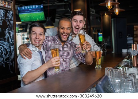 Beer evening in a pub. Male friends are drinking beer in a pub after working day and have great emotions. Beer glasses.  Beer pub concept. Men football and beer