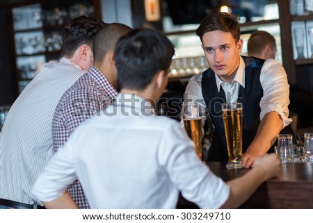 Beer evening in a pub. Portrait of young and handsome barman in a pub. Beer glasses.  Beer football pub bar concept.