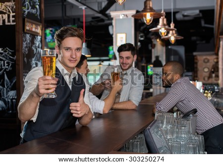 Beer evening in a pub. Portrait of young and handsome man drinking beer in a pub with his friends. Beer glasses.  Beer football pub concept.
