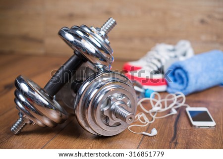 Sport equipment. Sport shoes, water towel and earphones on wooden background. Sport fitness background
