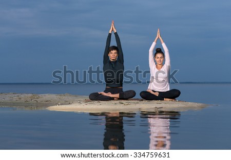 Perfect yoga. Beautiful young couple pair is balancing in lotus doing yoga. Pair yoga concept. Yoga flexibility outdoor class workout. Healthy yoga lifestyle
