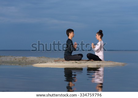 Perfect yoga. Beautiful young couple pair is balancing in lotus doing yoga. Pair yoga concept. Yoga flexibility outdoor class workout. Healthy yoga lifestyle