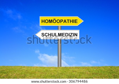 Street Sign showing homeopathy or medicine in german language in front of blue sky on green grass