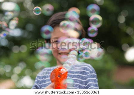 Blur of Cute Asian child Shooting Bubbles from Bubble Gun in the park