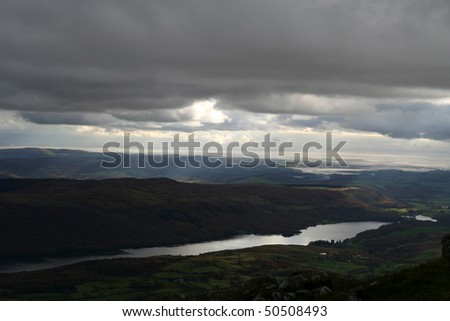 Overcast, Dark  Day. Dark clouds let sunlight trough. Coniston Water and Morcambe Bay seen from the top of Coniston Old Man.